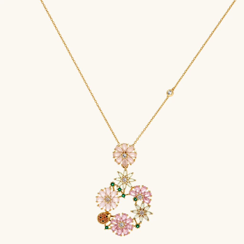 14K gold plated jewelry set with pink and green cubic zirconia flowers arranged in wreath design on cream background