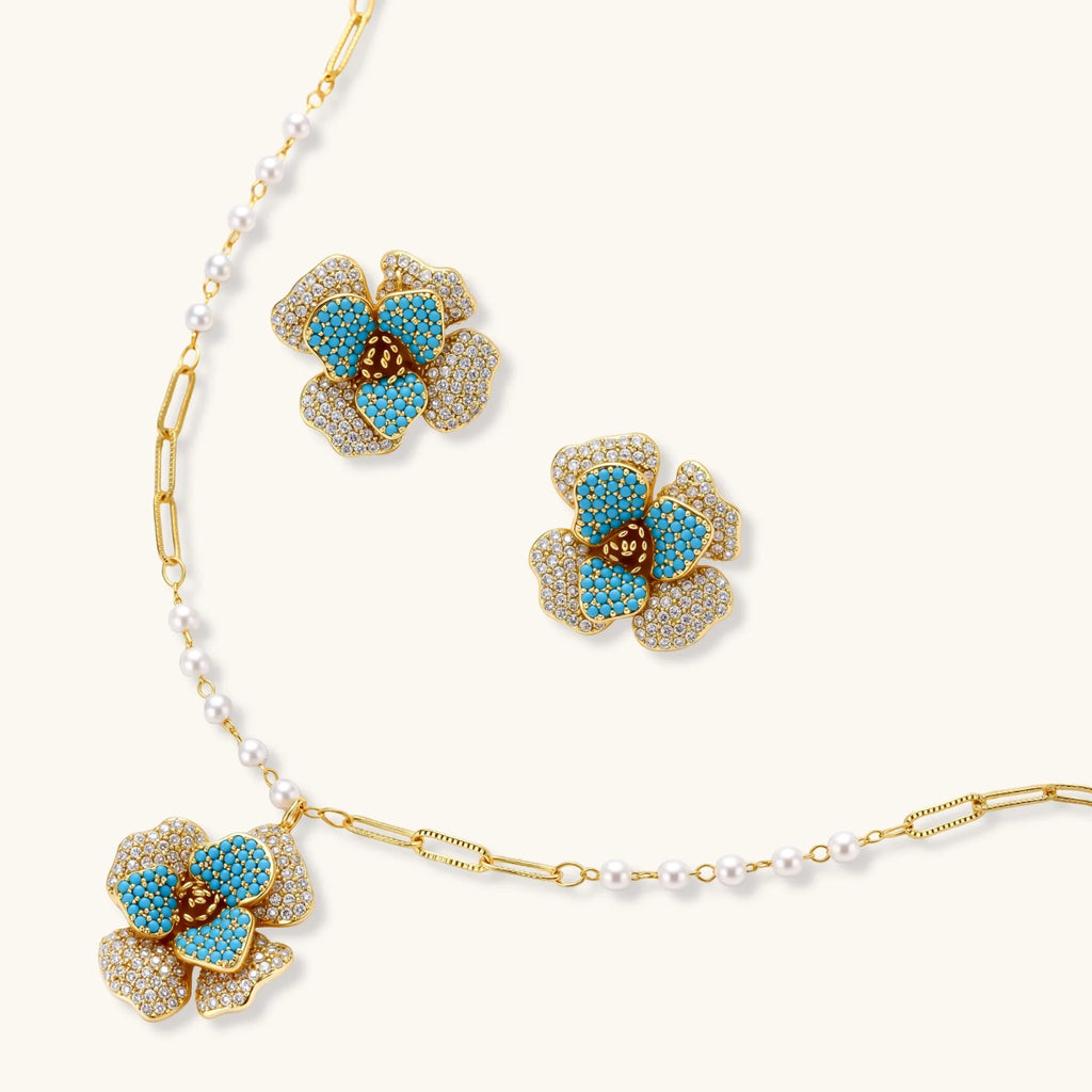 14K gold-plated floral jewelry set with blue cubic zirconia centers and pearl chain details on white background.