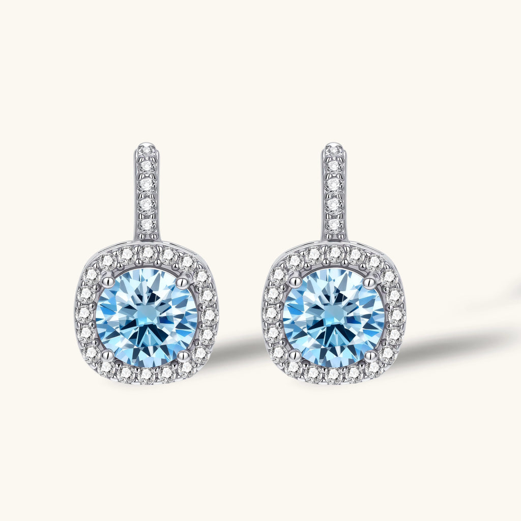 Sterling silver drop earrings featuring cushion-cut blue moissanite stones surrounded by sparkling halo settings