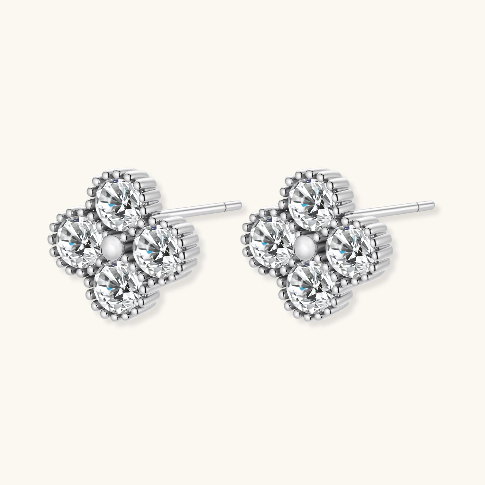 Dainty sterling silver quatrefoil stud earrings with four brilliant moissanite stones and center accent on white background.