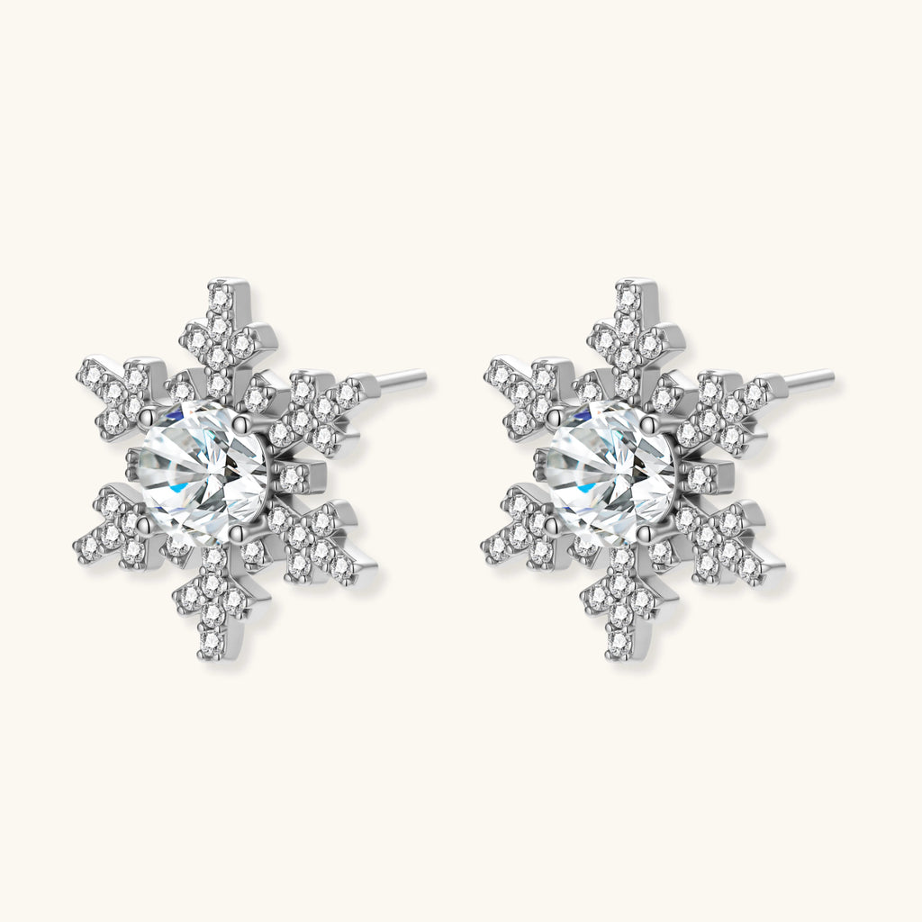 Sterling silver snowflake stud earrings with brilliant moissanite centers and intricate geometric patterns on cream background