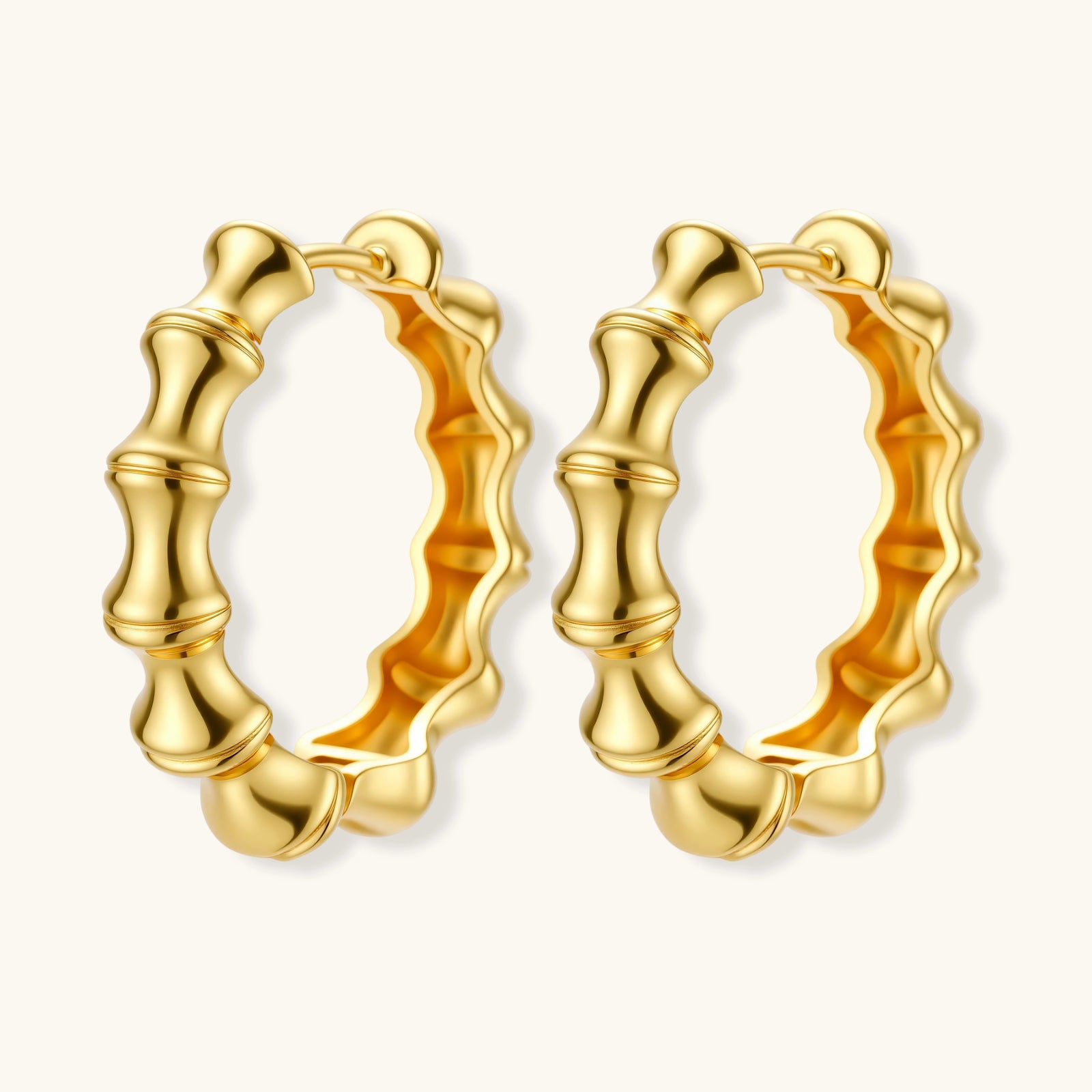 Close-up of gold-plated sterling silver hoop earrings with bamboo-inspired segmented design on white background.