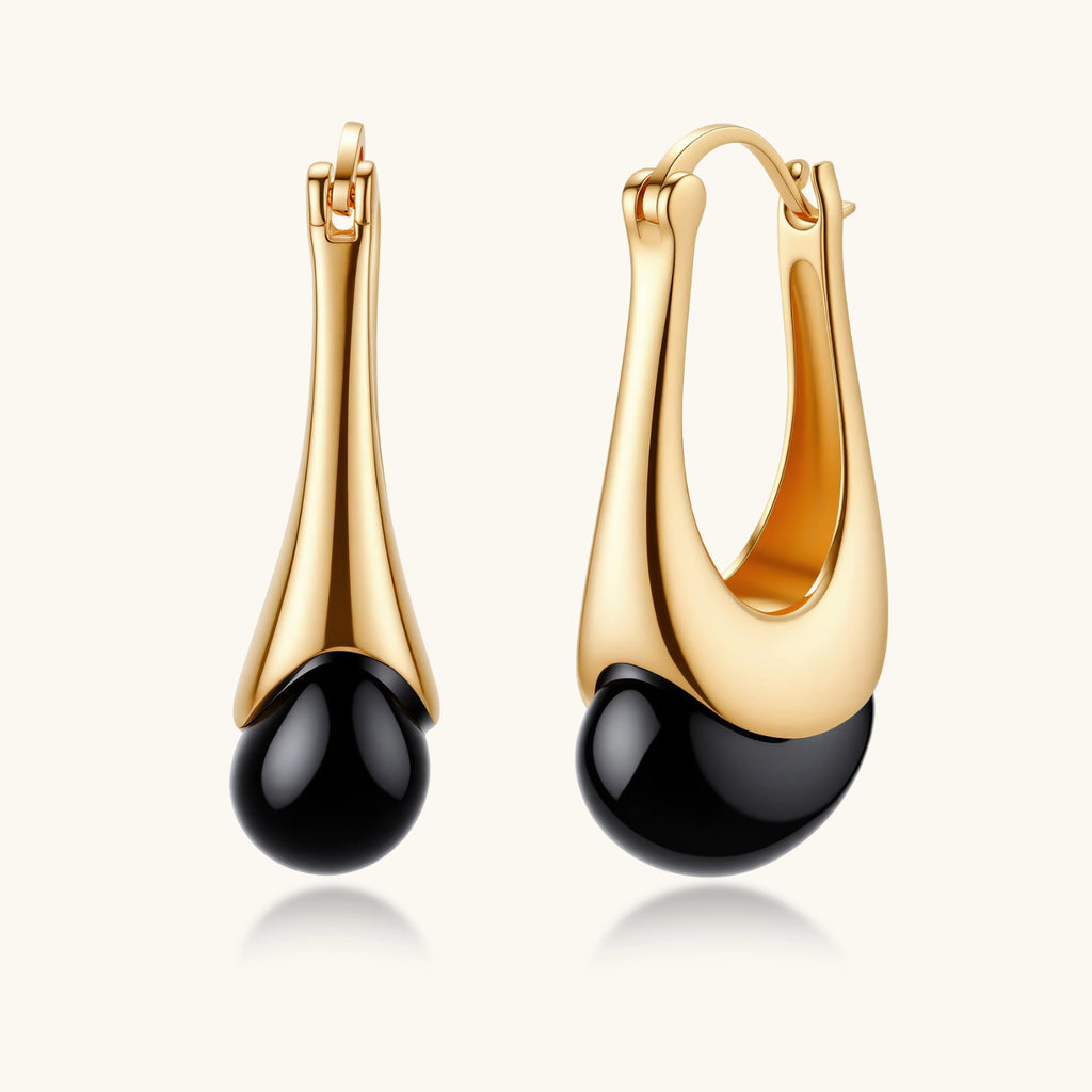 Gold-plated drop earrings featuring black agate stones with hoop closure on white background, showing elegant teardrop design.