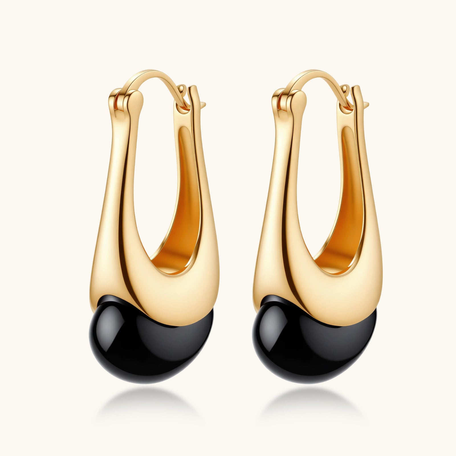 Gold-plated drop earrings featuring black agate stones with hoop closure on white background, showing elegant teardrop design.