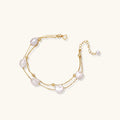 Double-strand gold bracelet with irregular baroque pearls and smooth freshwater pearls on cream background.