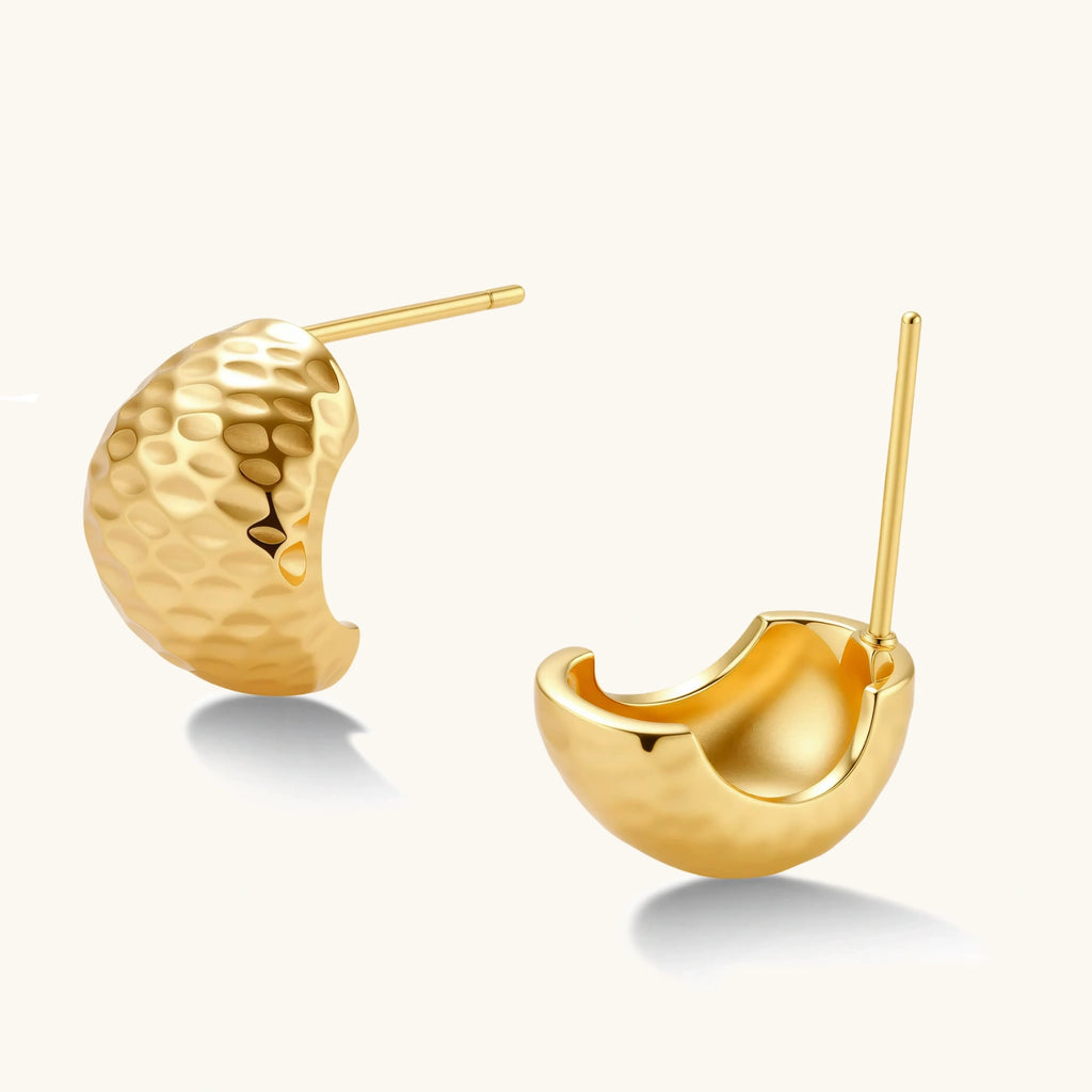 Pair of textured gold-plated sterling silver huggie earrings with dimpled surface finish on cream background.