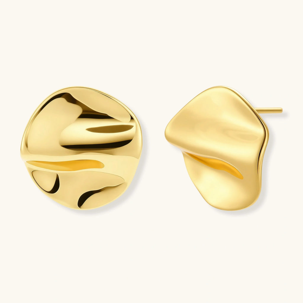Close-up of organic gold-plated sterling silver stud earrings with flowing sculptural design and curved cut-outs