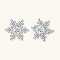 Sterling silver snowflake stud earrings with brilliant moissanite centers and intricate geometric patterns on cream background