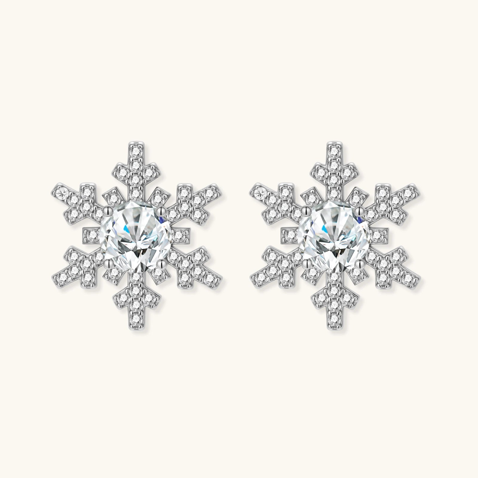 Sterling silver snowflake stud earrings with brilliant moissanite centers and intricate geometric patterns on cream background