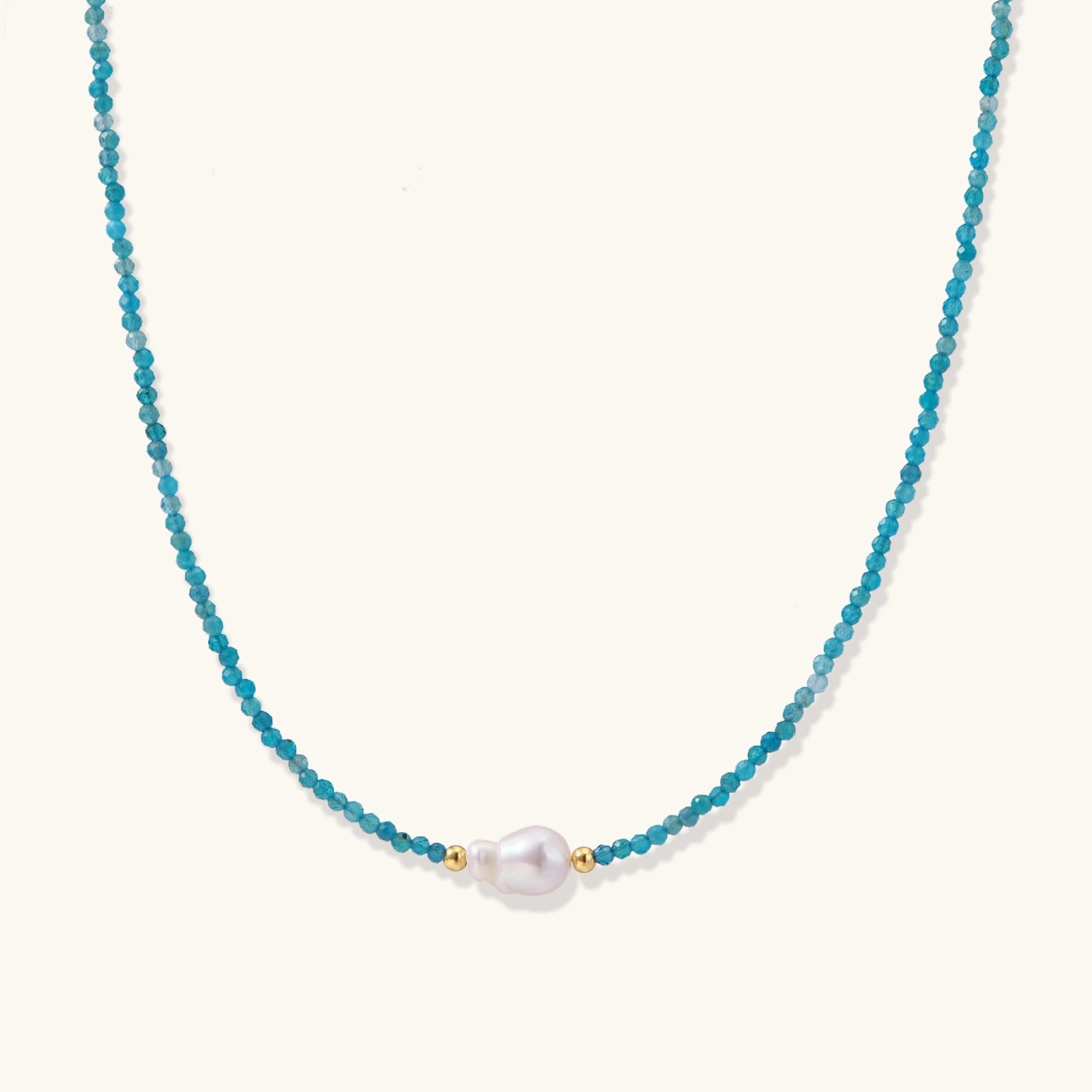 Delicate gold vermeil necklace with teal apatite beads and freshwater pearl on white background.