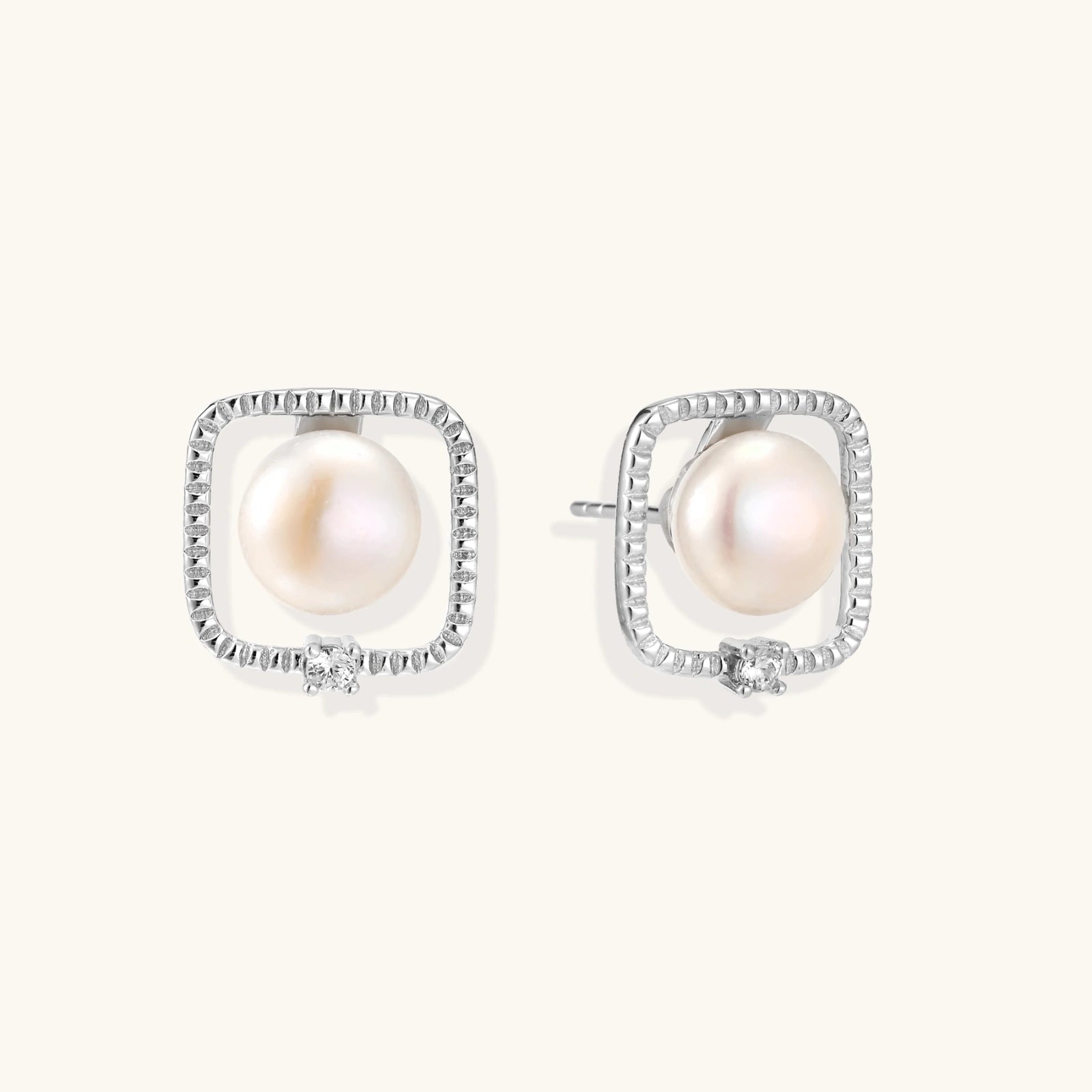 Rhodium-plated silver stud earrings with cushion frame, centered freshwater pearl, and tiny crystal accent