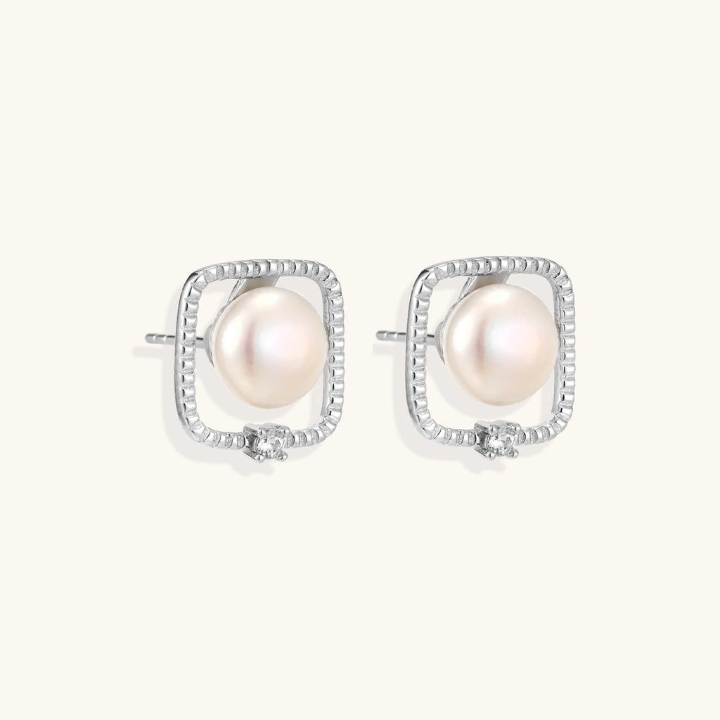 Rhodium-plated silver stud earrings with cushion frame, centered freshwater pearl, and tiny crystal accent