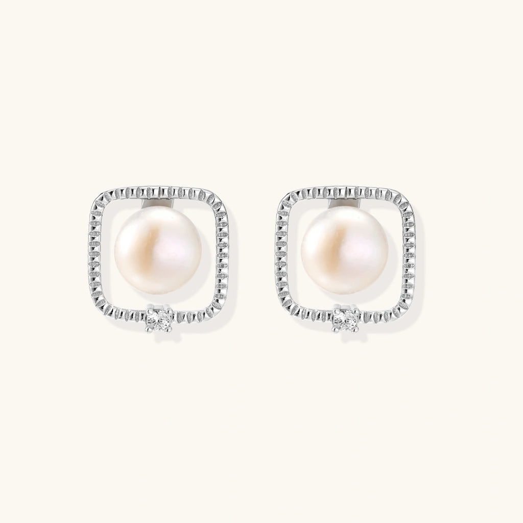 Rhodium-plated silver stud earrings with cushion frame, centered freshwater pearl, and tiny crystal accent