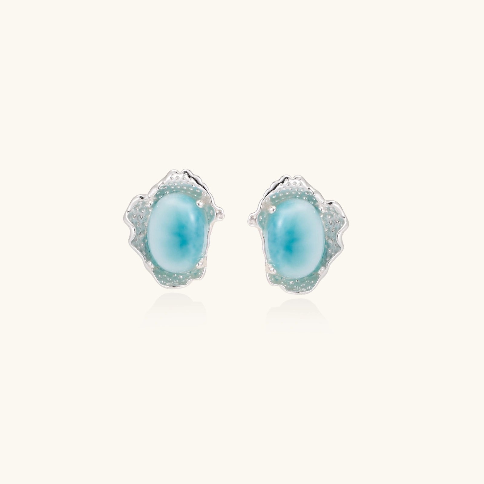 Oval larimar gemstone studs with ornate silver settings showing natural turquoise marbling on cream background