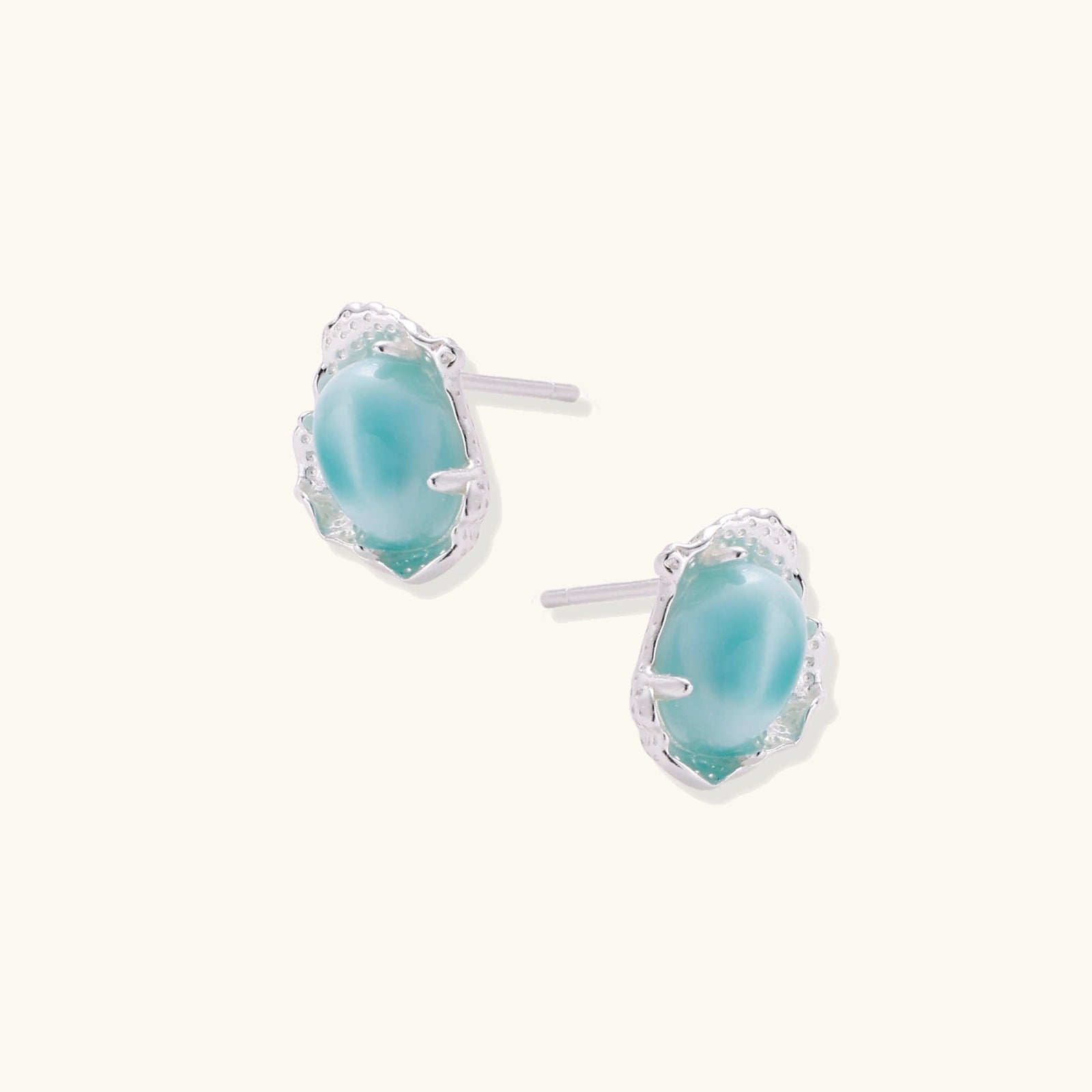 Oval larimar gemstone studs with ornate silver settings showing natural turquoise marbling on cream background