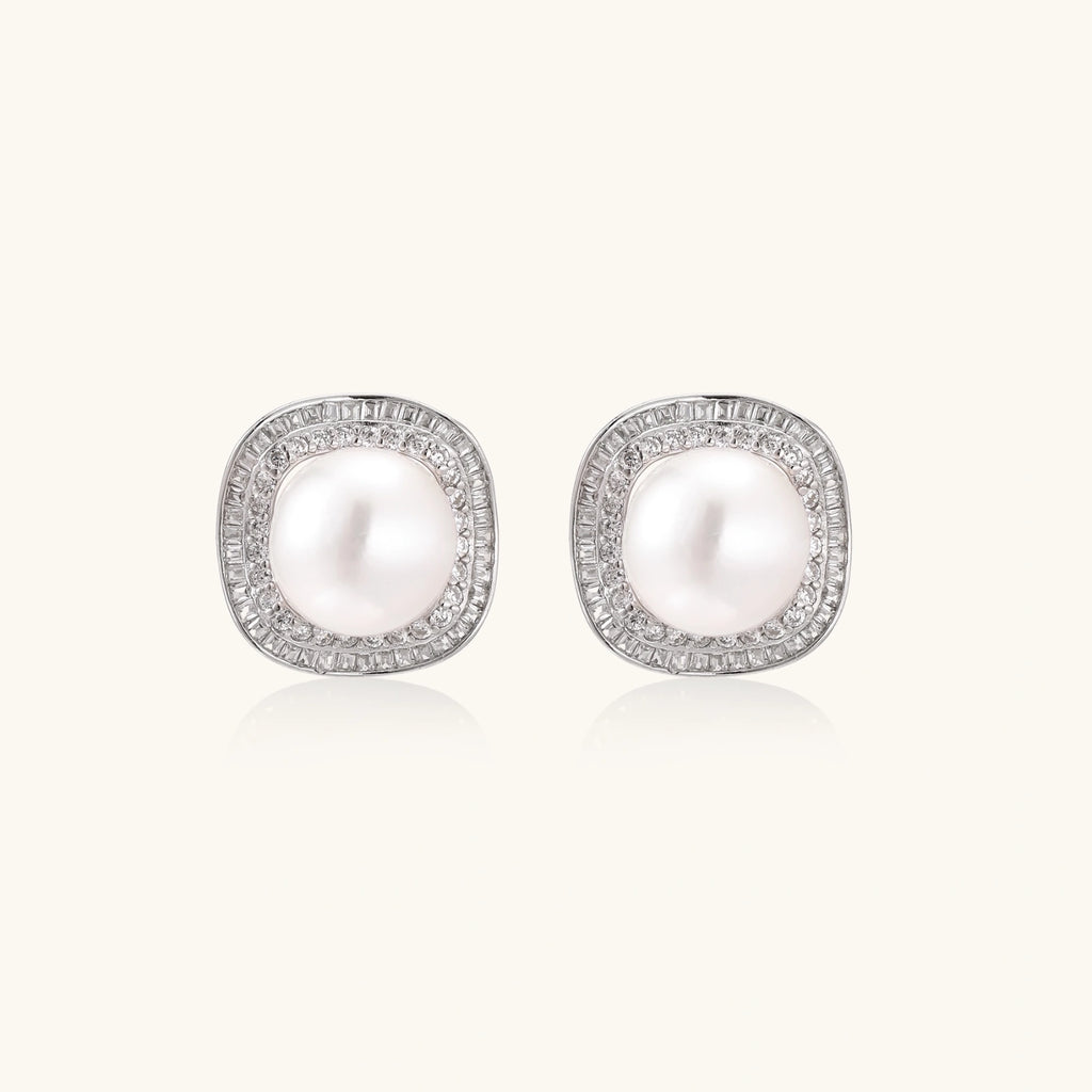 Rhodium-plated sterling silver stud earrings with round freshwater pearls surrounded by geometric crystal halos on cream background.