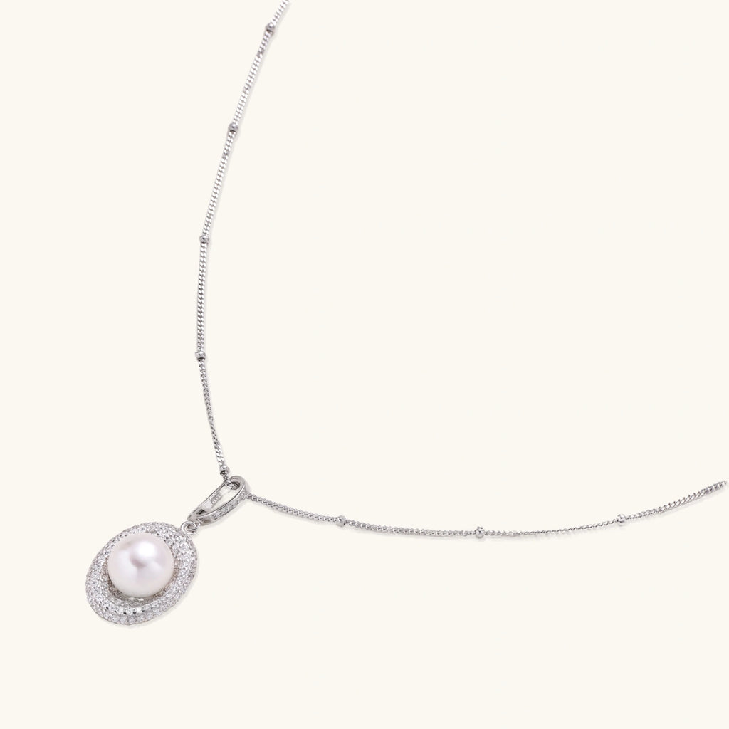 Oval sterling silver pendant with crystal halo surrounding a white freshwater pearl on delicate chain