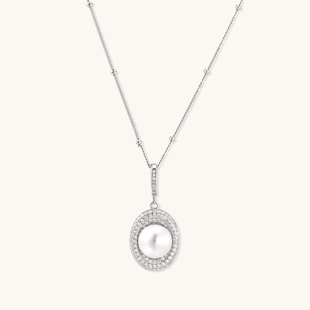 Oval sterling silver pendant with crystal halo surrounding a white freshwater pearl on delicate chain