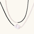 Double-strand necklace with black faceted quartz and white pearls featuring an oversized baroque pearl centerpiece