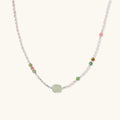 Delicate pearl necklace with pale green serpentine jade centerpiece and colorful agate beads on cream background