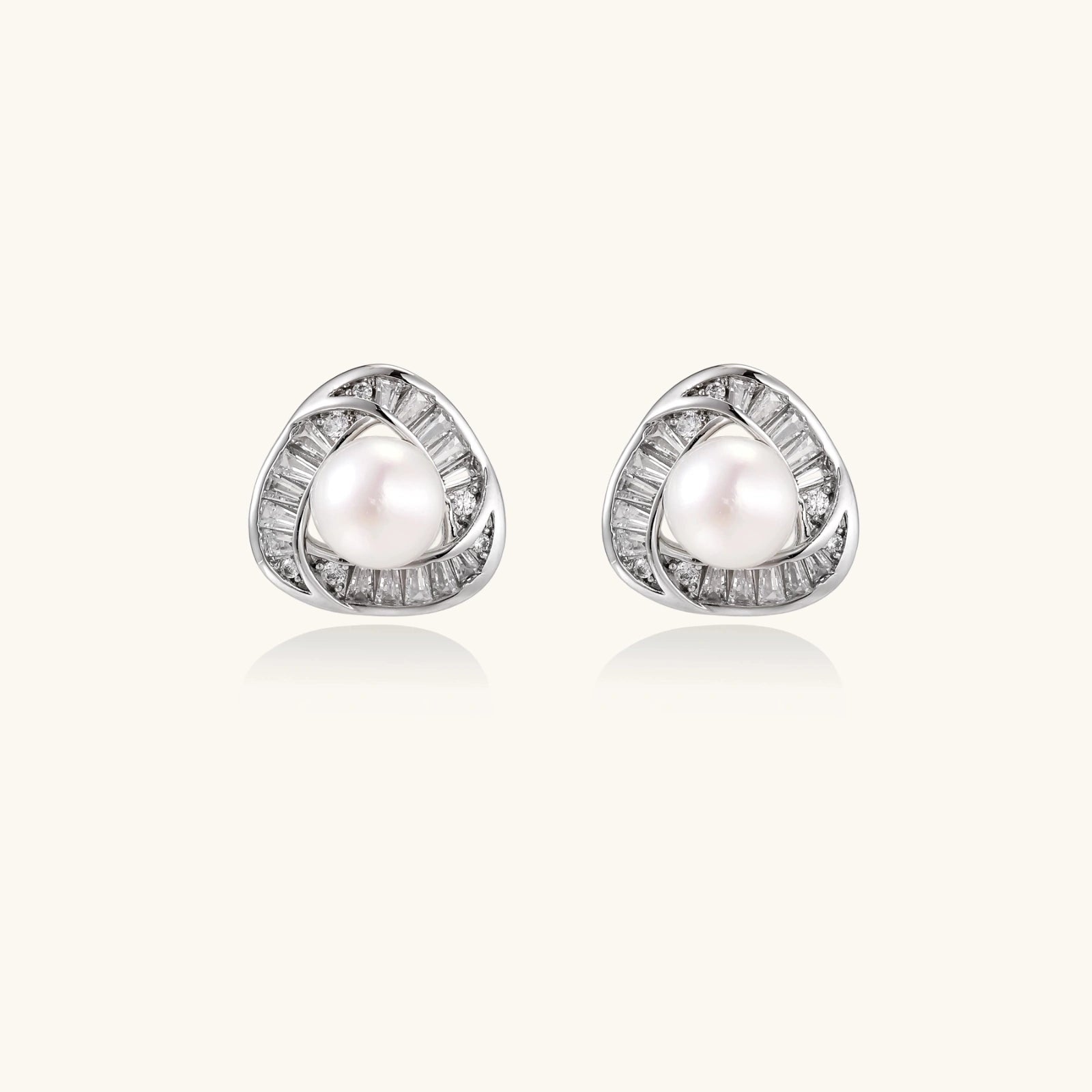 Triangular white gold plated stud earrings with central freshwater pearl and baguette-cut stones on white background