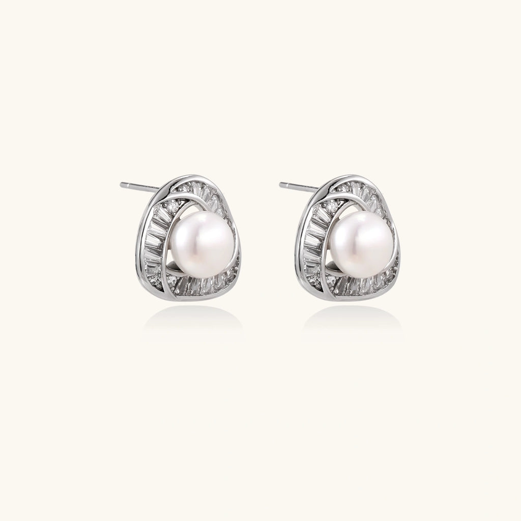 Triangular white gold plated stud earrings with central freshwater pearl and baguette-cut stones on white background