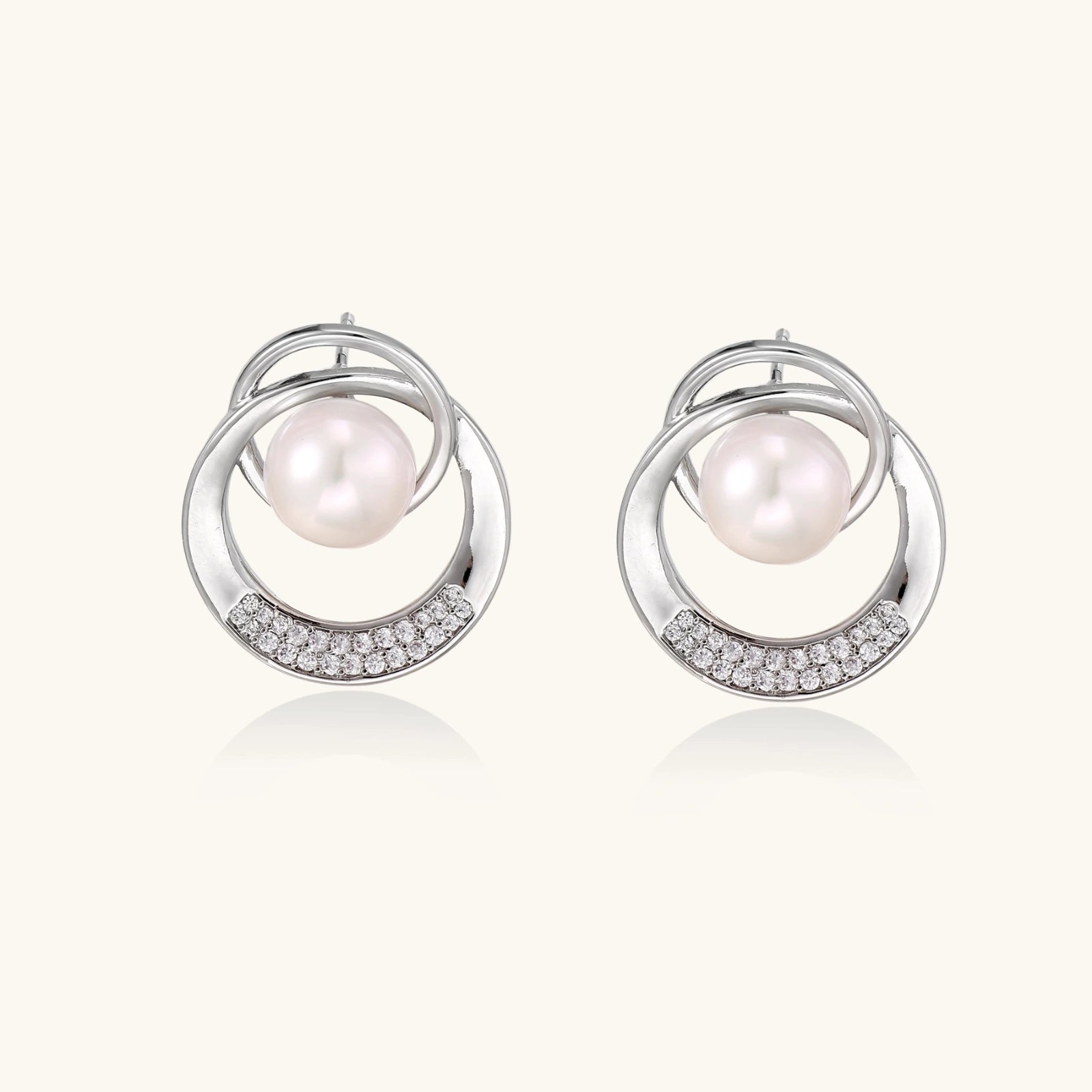 White gold-plated brass earrings with circular design, freshwater pearl center, and diamond accents