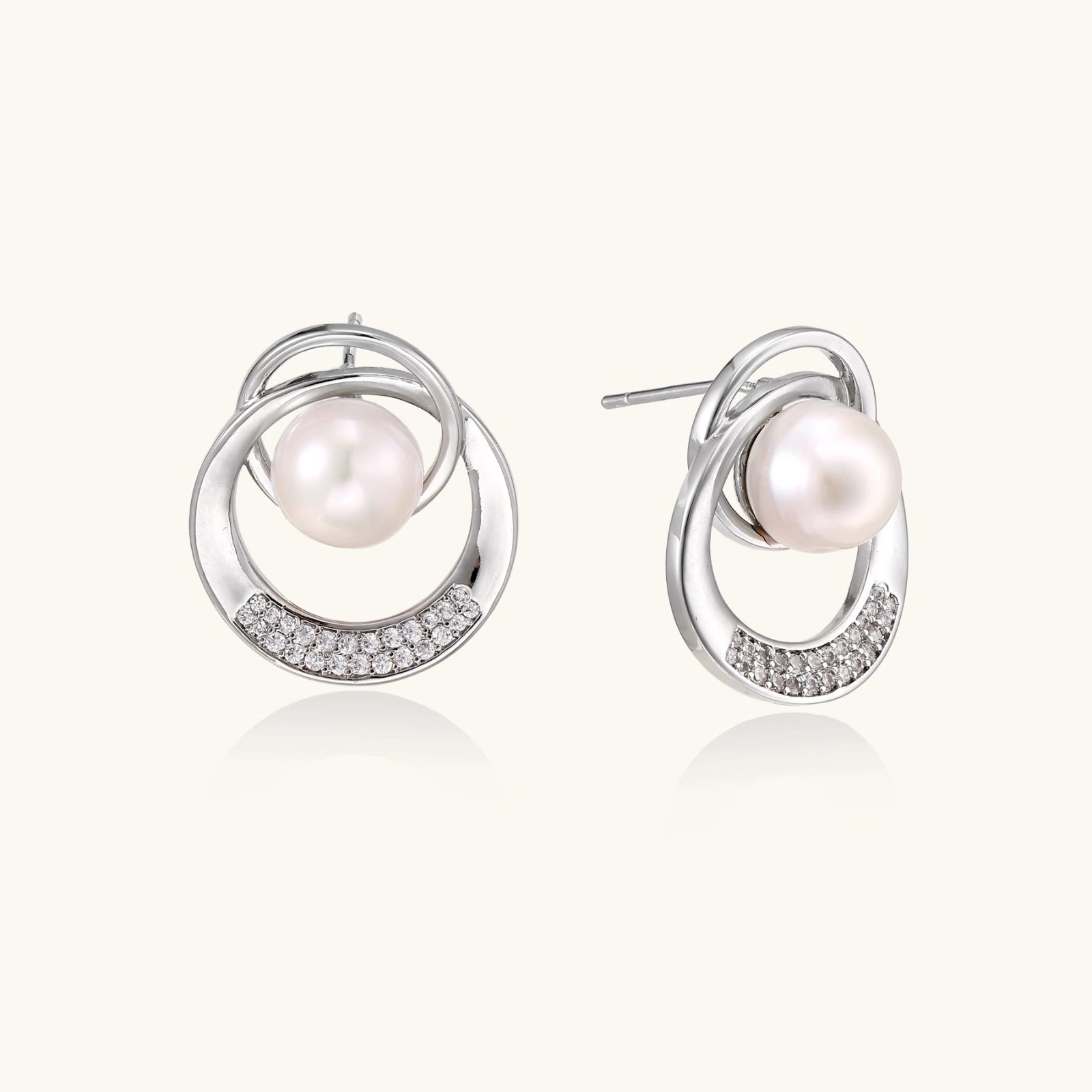 White gold-plated brass earrings with circular design, freshwater pearl center, and diamond accents