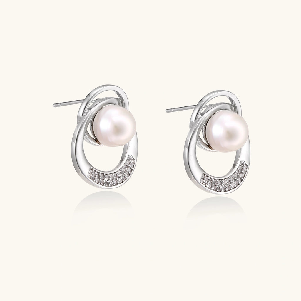 White gold-plated brass earrings with circular design, freshwater pearl center, and diamond accents