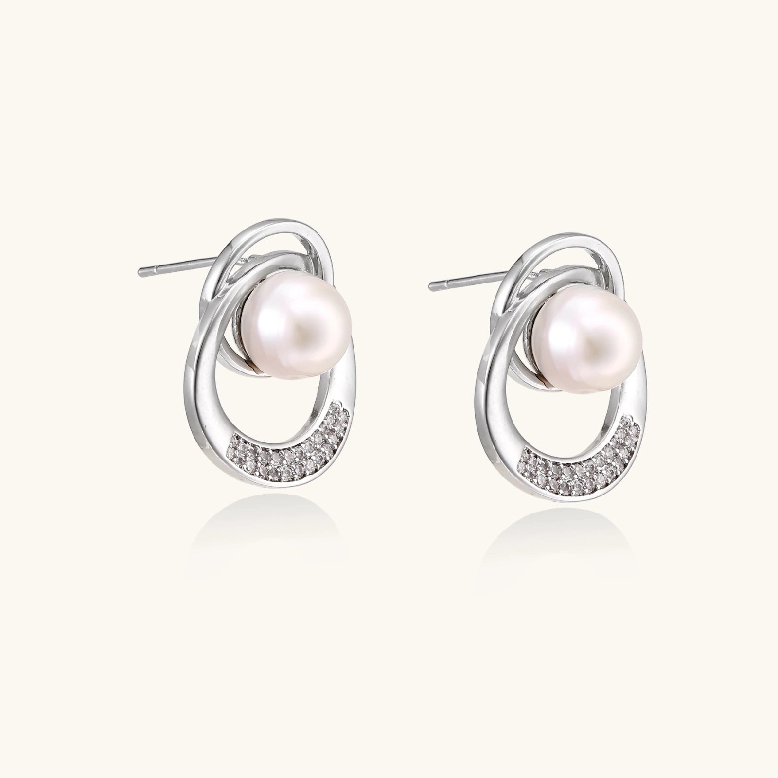 White gold-plated brass earrings with circular design, freshwater pearl center, and diamond accents