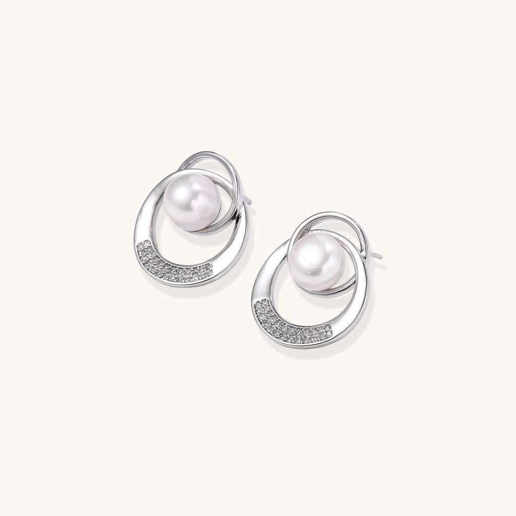 White gold-plated brass earrings with circular design, freshwater pearl center, and diamond accents