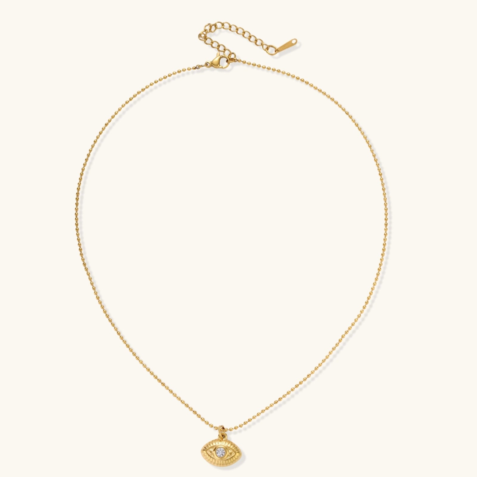 Layered necklace with green stone beads, gold spacers, white accents, and protective eye pendant on cream background.