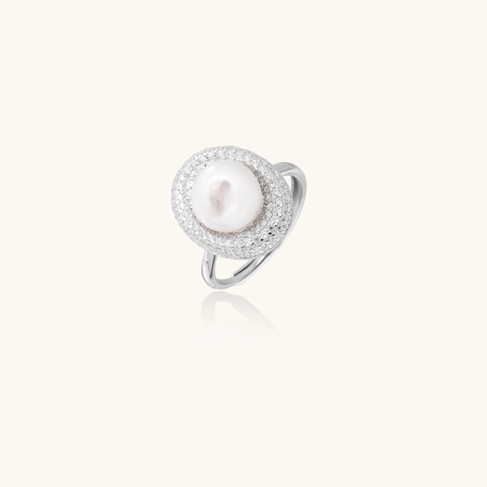 Silver ring with lustrous white pearl center surrounded by sparkling crystal halo on light background.